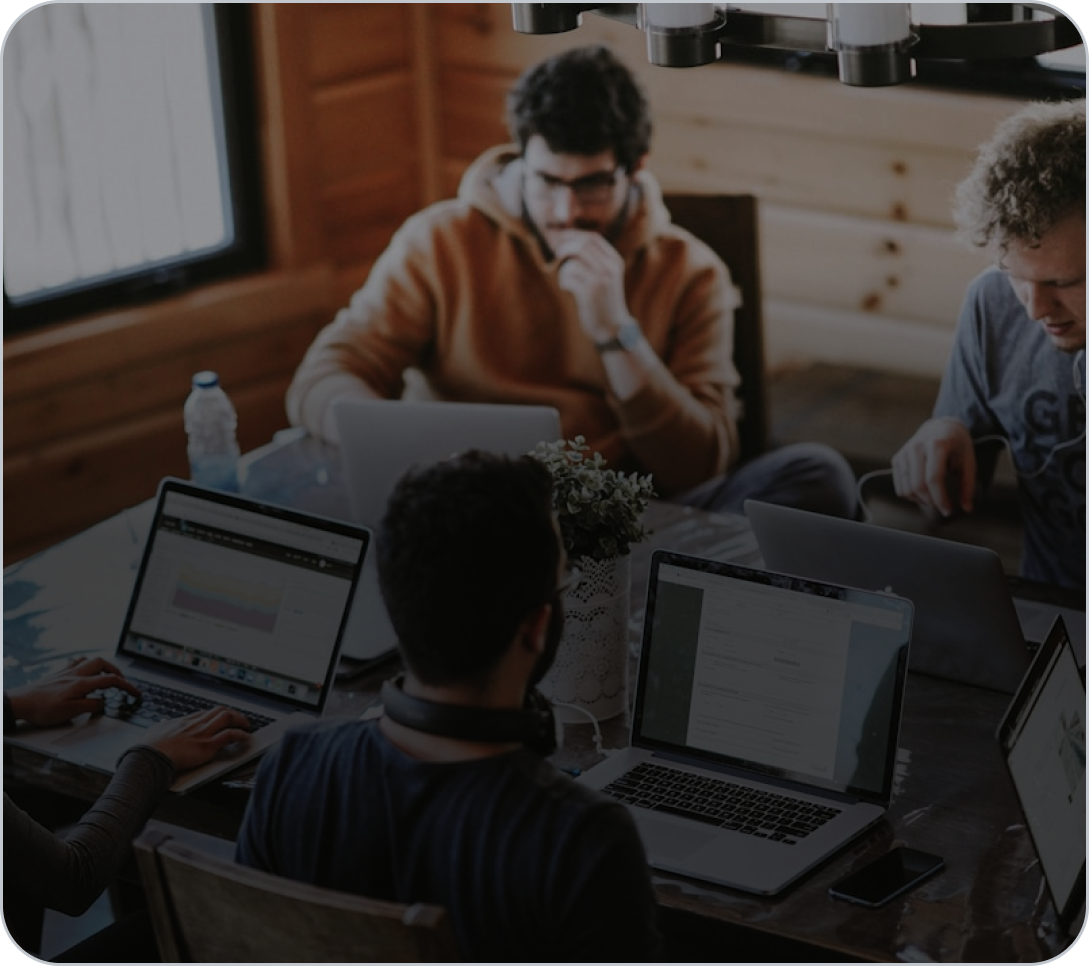 Stock image of workers at laptops with a grey overlay.