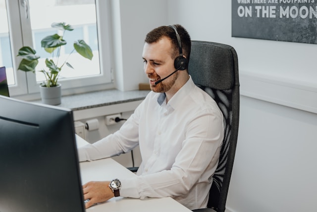 seo-galaxy-GQ6bUqDNjZY-unsplash - GeoPlugin - Resources A customer support agent sitting in front of a work desk.