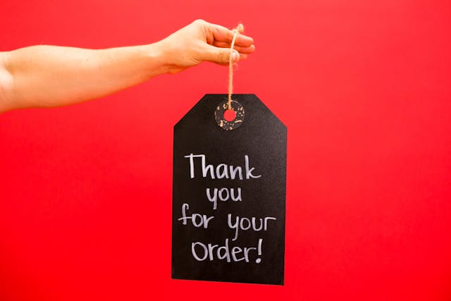 pexels-rdne-7564234 - GeoPlugin - Resources Image showing a woman holding a tag that adds a touch of personalization as it says “Thank you for your order.”